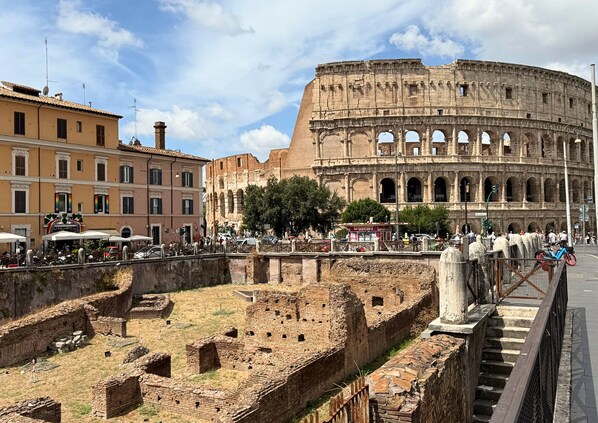 The Colosseum with surrounding ancient ruins and modern buildings. - First Floor (Rome)