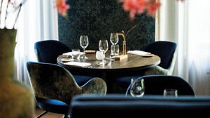 A round dining table with four chairs, a vase with flowers, and a decorative centerpiece.