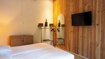 Een hotelkamer met een bed, een houten wandpaneel, een flatscreen televisie, een spiegel en een klein kastje.