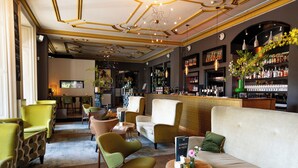 A bar area with seating, a television, and a variety of bottles and glasses on shelves.