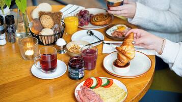 Una mesa de desayuno con diversas comidas, un croissant, un vaso de jugo y una taza de té.