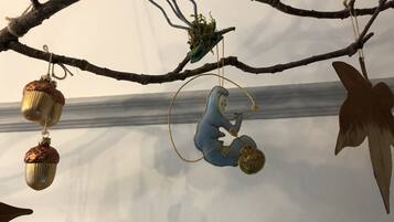 Une branche ornée de divers éléments décoratifs, notamment un éléphant bleu, des glands dorés et un papillon.