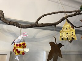 A branch with a rabbit ornament and a golden birdhouse.
