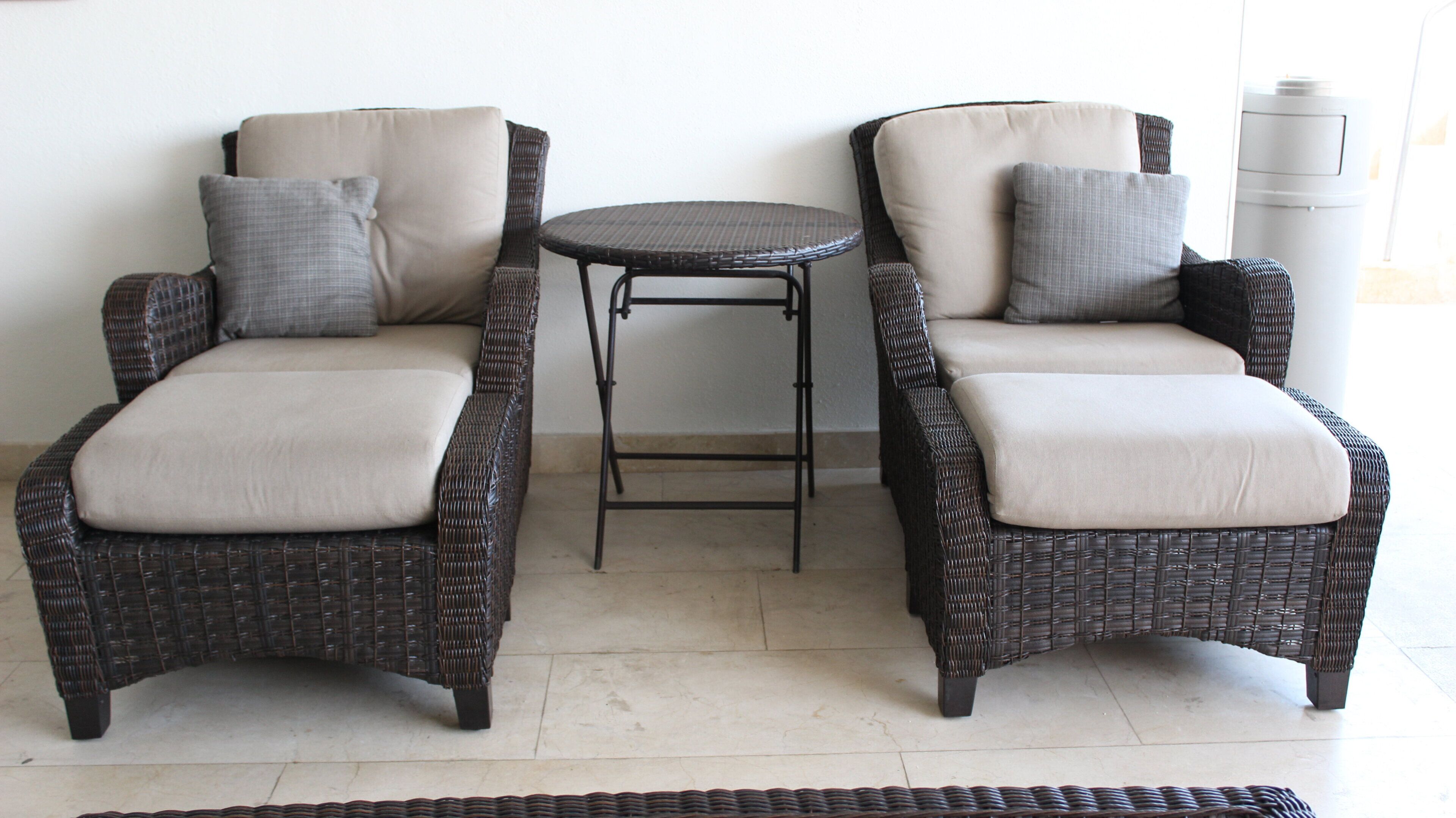 A room with two wicker chairs and a small round table.