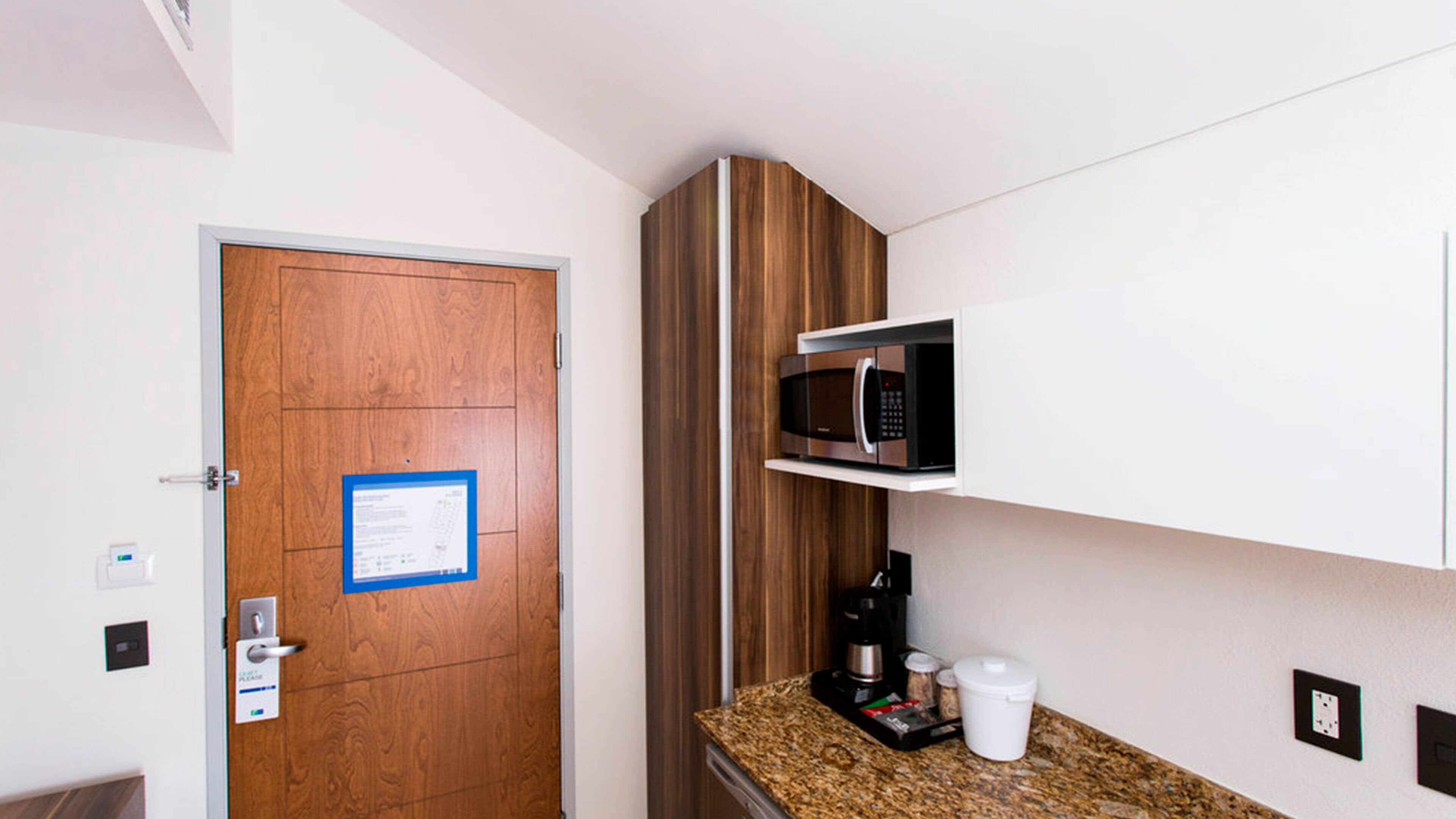 A compact kitchen with a microwave, coffee maker, and a small countertop.