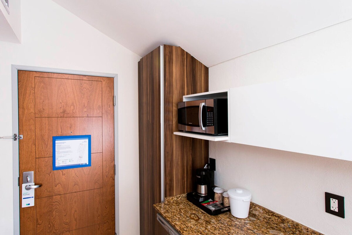 A compact kitchen with a microwave, coffee maker, and a small countertop.