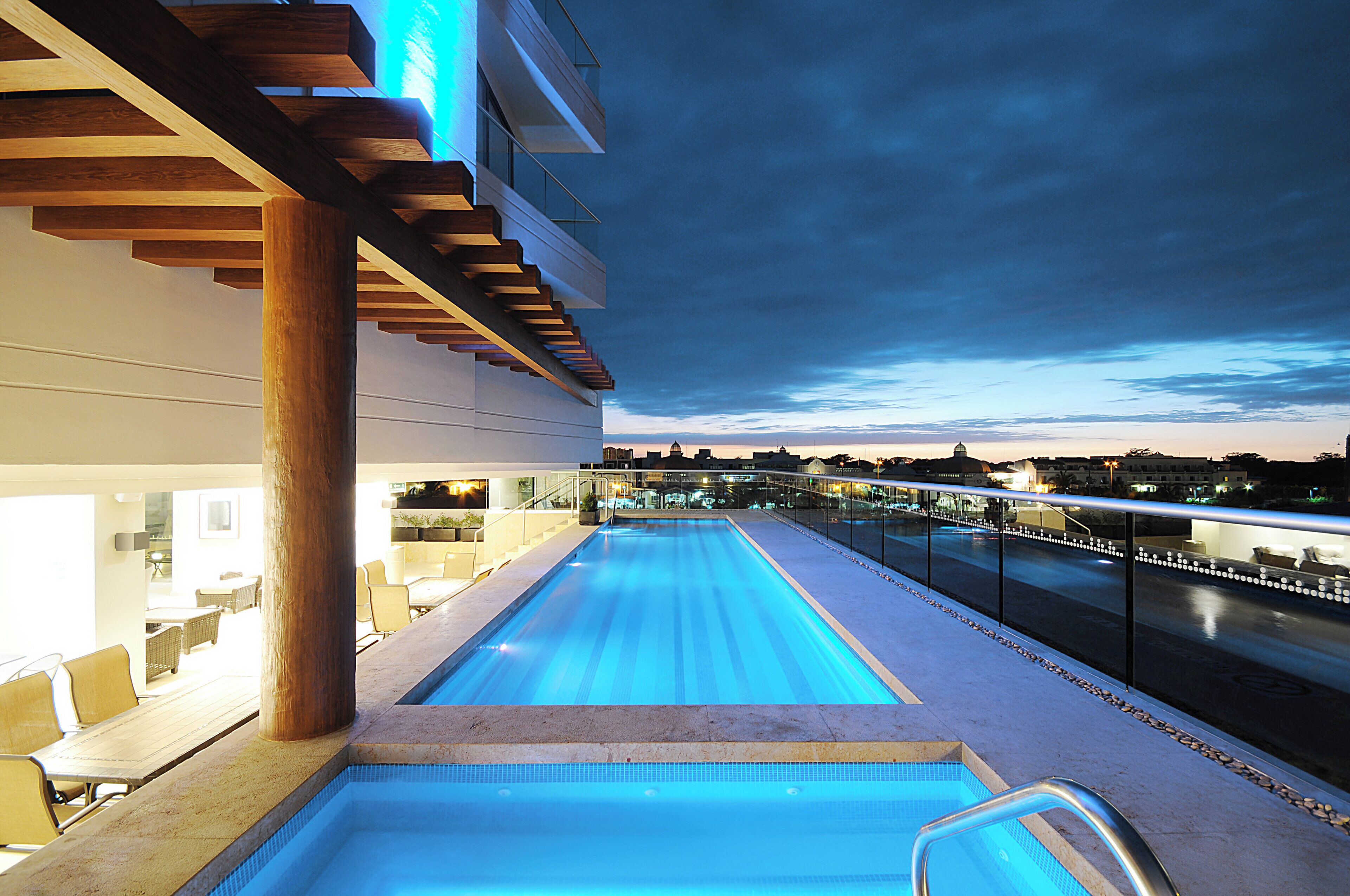 A swimming pool with a view of a cityscape at dusk.
