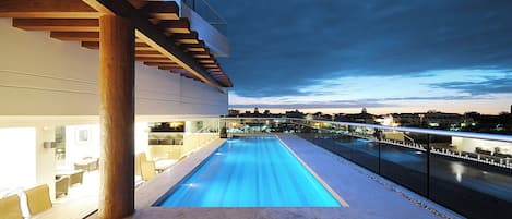 A swimming pool with a view of a cityscape at dusk.