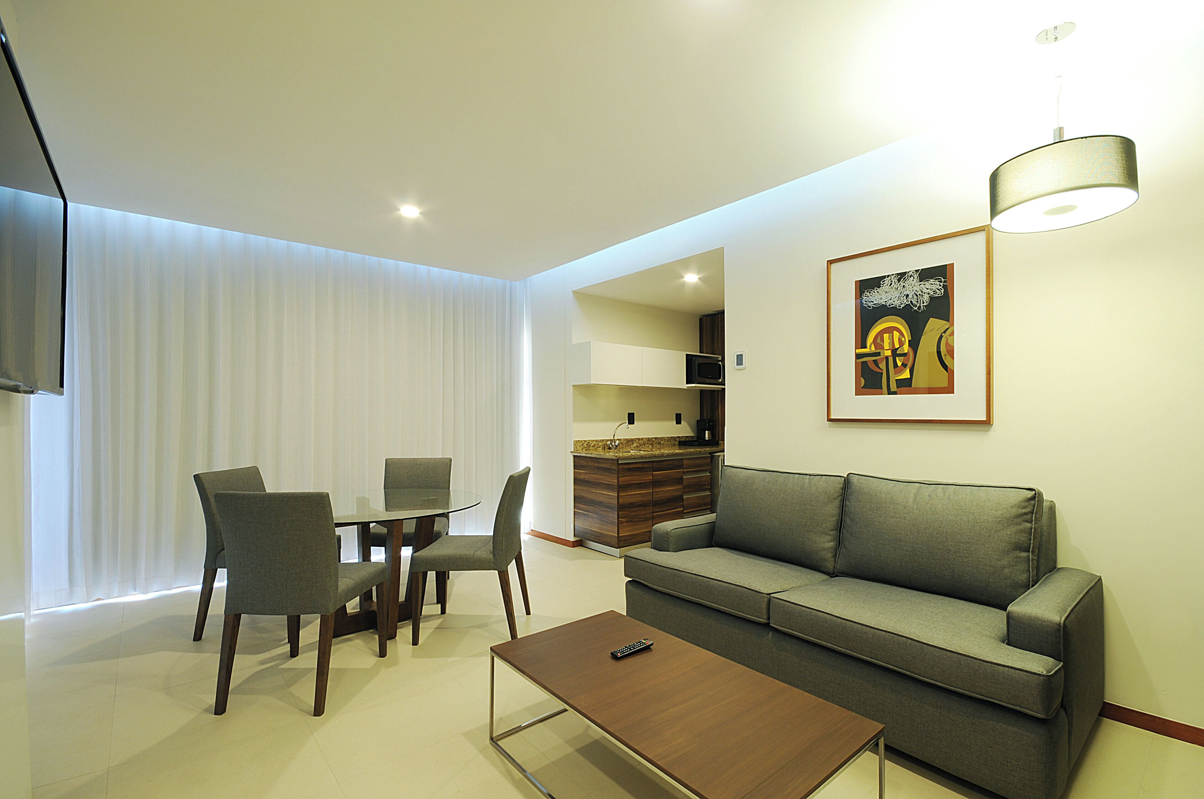 A modern living room with a sofa, a coffee table, and a dining area with chairs.