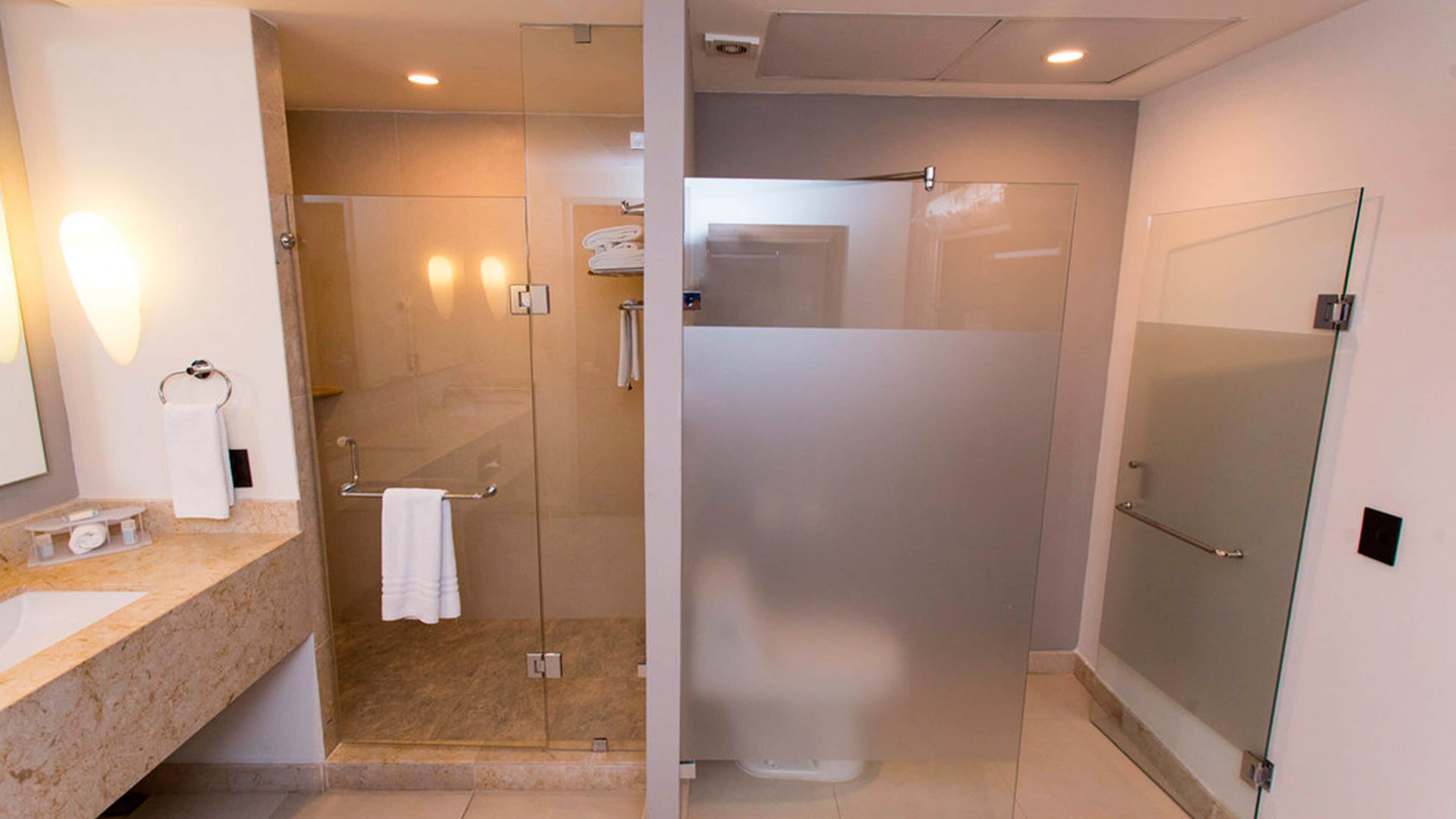 Un baño moderno con cabina de ducha de vidrio, un lavamanos con encimera de mármol y un espejo.