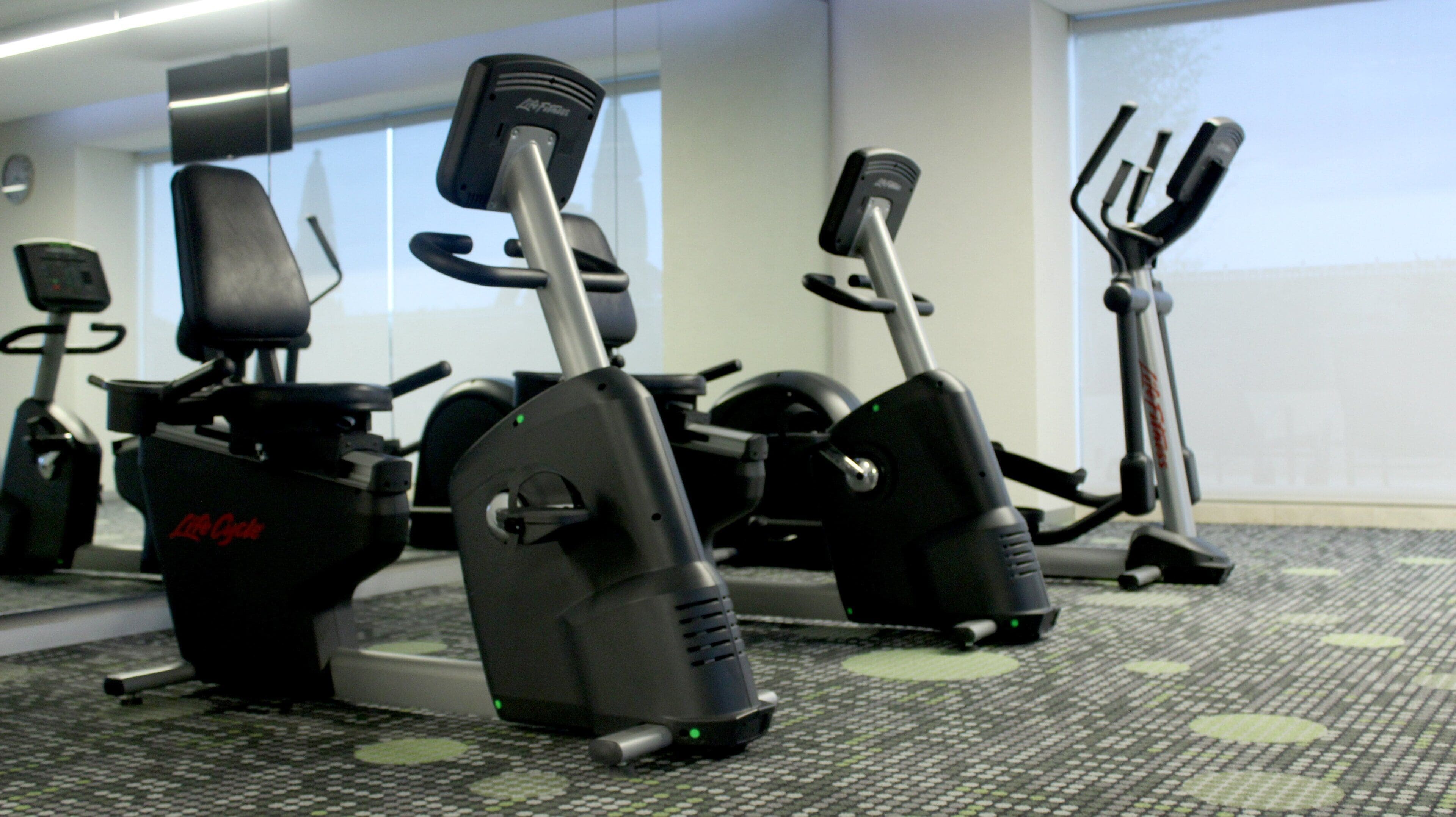 A row of stationary bikes in a gym with a patterned floor.