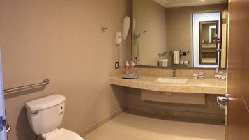 A bathroom with a toilet, a sink, a mirror, and a hand dryer.