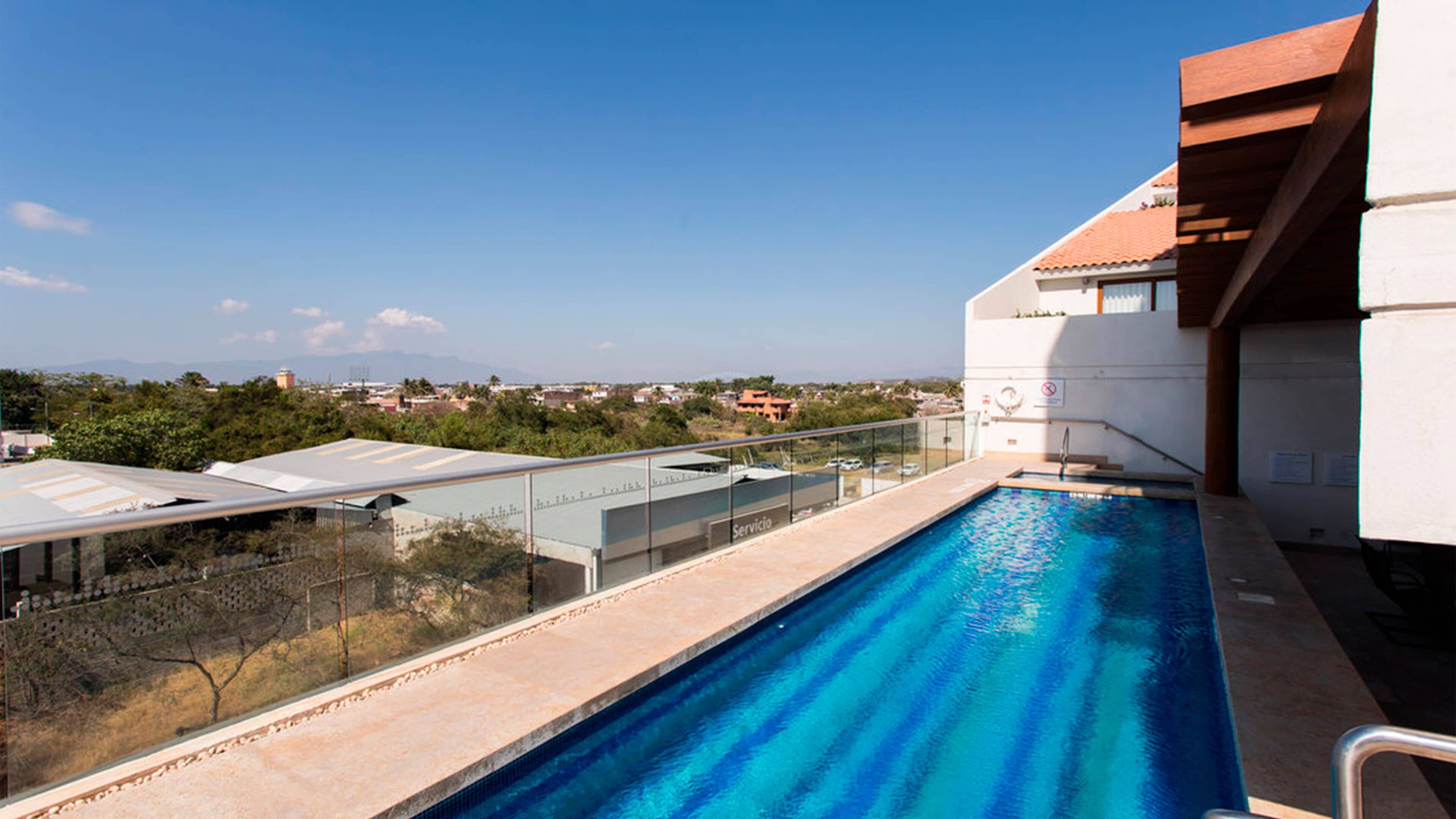 A rooftop swimming pool with a clear view of the surrounding landscape and distant buildings.
