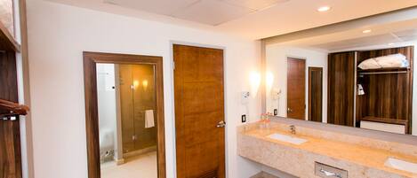 Un baño de hotel con puerta de madera, un espejo grande, un lavabo y un perchero para toallas.