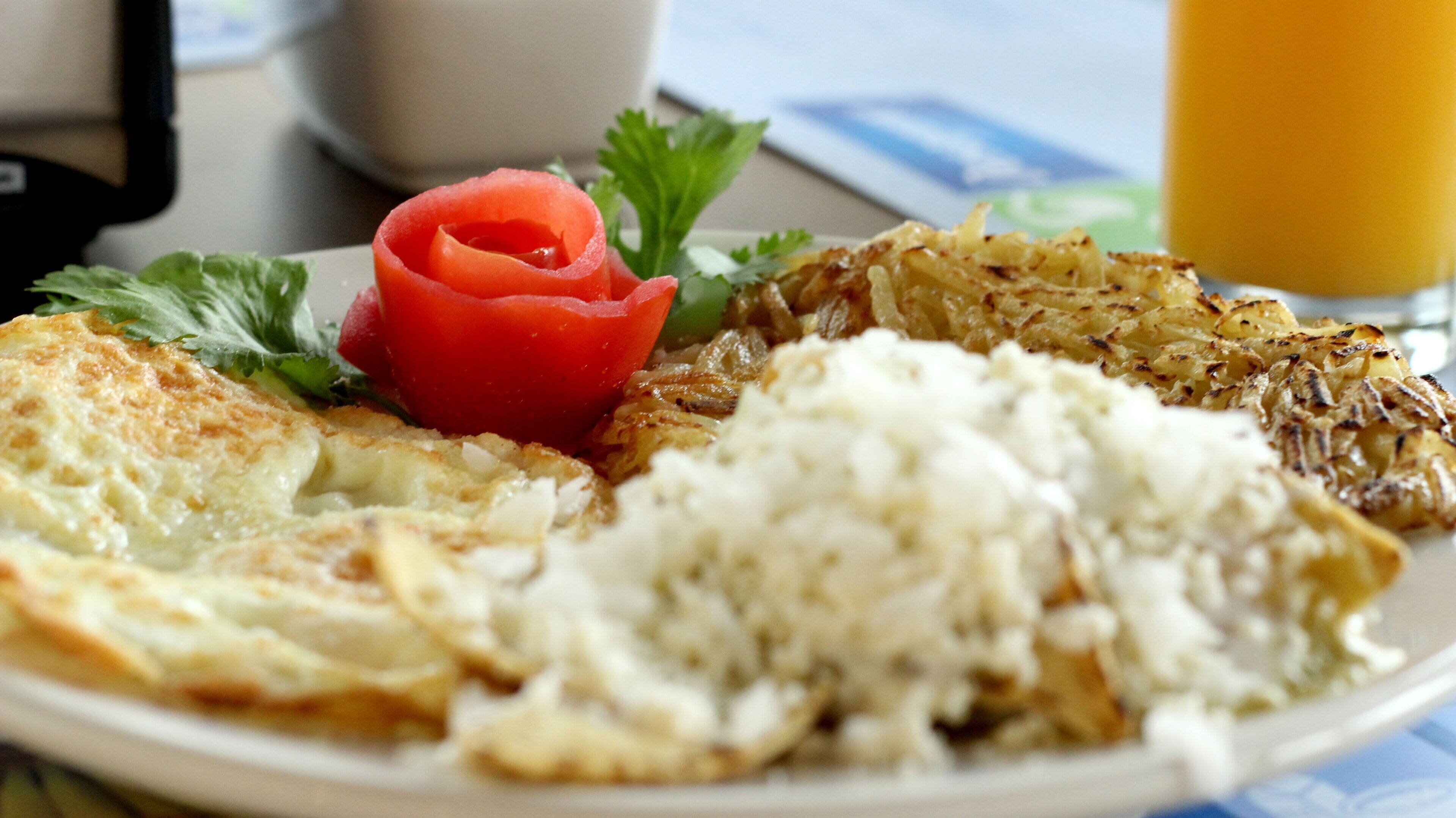 A plate of food with eggs, potatoes, and a tomato garnish.