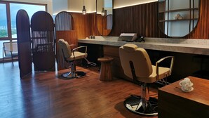 A modern hair salon with wooden floors, two hairdressing chairs, a large mirror, and a counter with a laptop and phone. - Holiday Inn Express Puerto Vallarta by IHG (Puerto Vallarta)