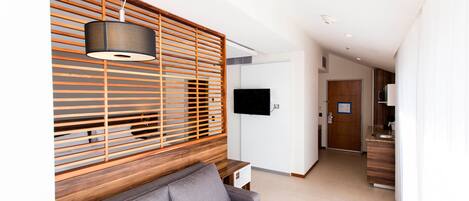 A modern living room with a grey sofa, wooden slatted wall, and a hanging lamp.