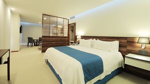 A hotel room with a large bed, a bedside table with a lamp, a desk with a chair, and a view of a balcony with curtains. - Holiday Inn Express Puerto Vallarta by IHG (Puerto Vallarta)
