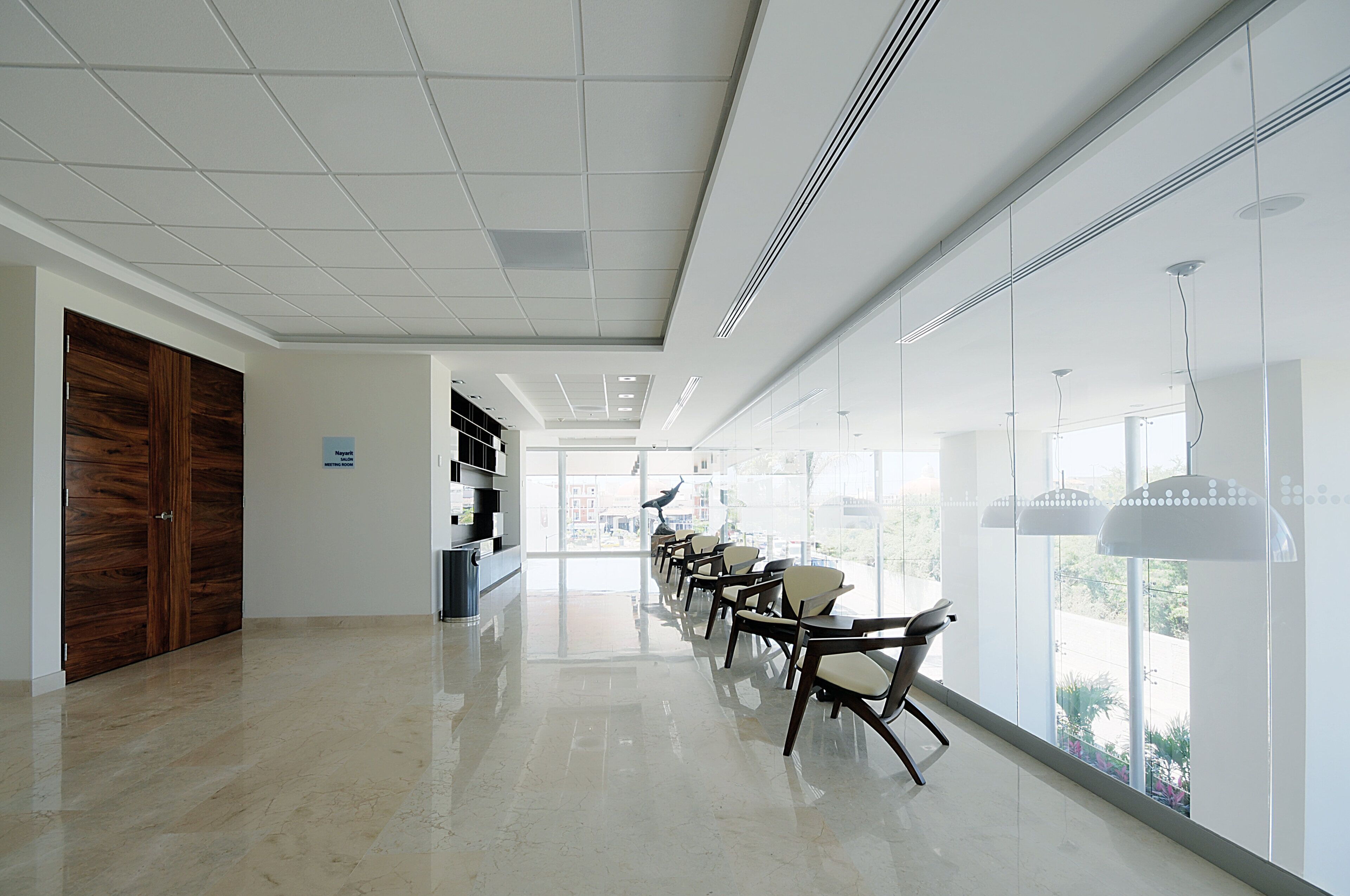 Un hall d’entrée spacieux et bien éclairé, doté d’un plancher ciré, d’un comptoir de réception et d’un espace détente avec des fauteuils.