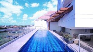 A swimming pool with a view of a cityscape, a covered outdoor seating area, and a building with a red roof. - Holiday Inn Express Puerto Vallarta by IHG (Puerto Vallarta)