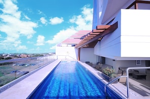 A swimming pool with a view of a cityscape, a covered outdoor seating area, and a building with a red roof. - Holiday Inn Express Puerto Vallarta by IHG (Puerto Vallarta)