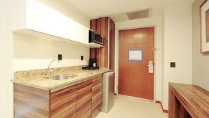 A compact kitchen with a granite countertop, stainless steel sink, and wooden cabinets. - Holiday Inn Express Puerto Vallarta by IHG (Puerto Vallarta)