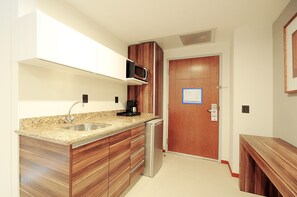 A compact kitchen with a granite countertop, stainless steel sink, and wooden cabinets. - Holiday Inn Express Puerto Vallarta by IHG (Puerto Vallarta)