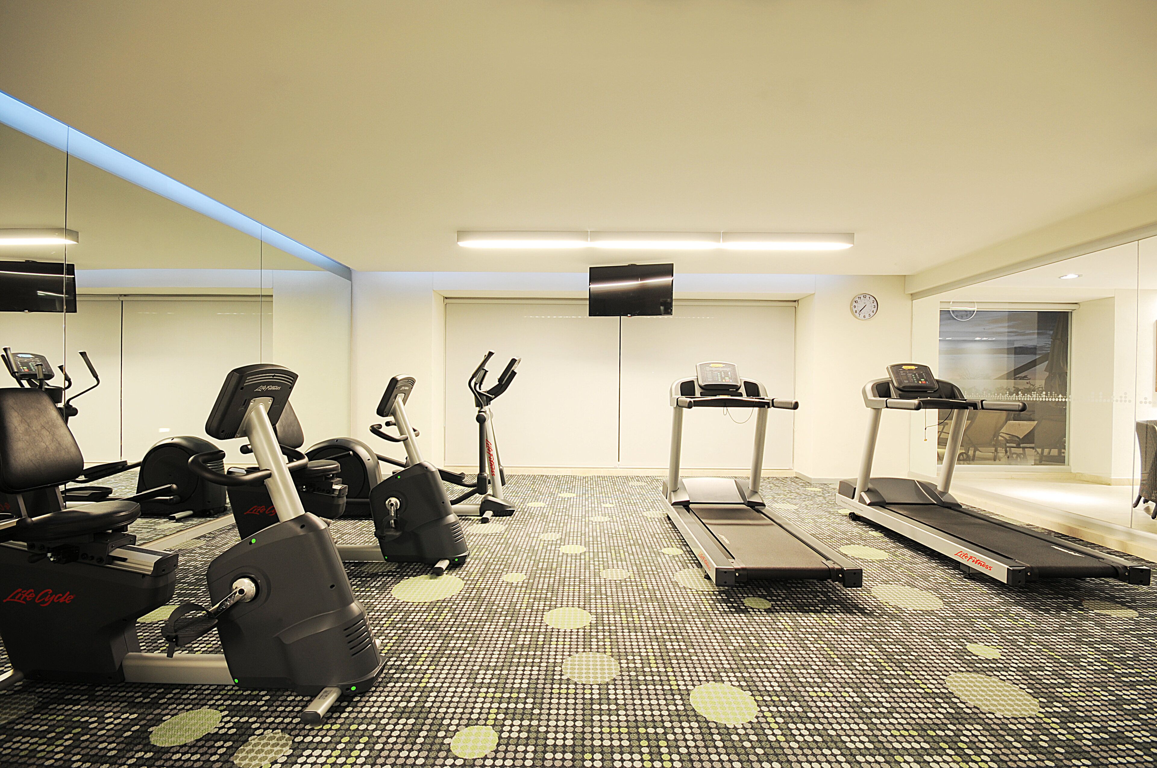 Un gimnasio con diversos equipos de ejercicio, incluyendo cintas de correr, bicicletas estáticas y máquinas de pesas.