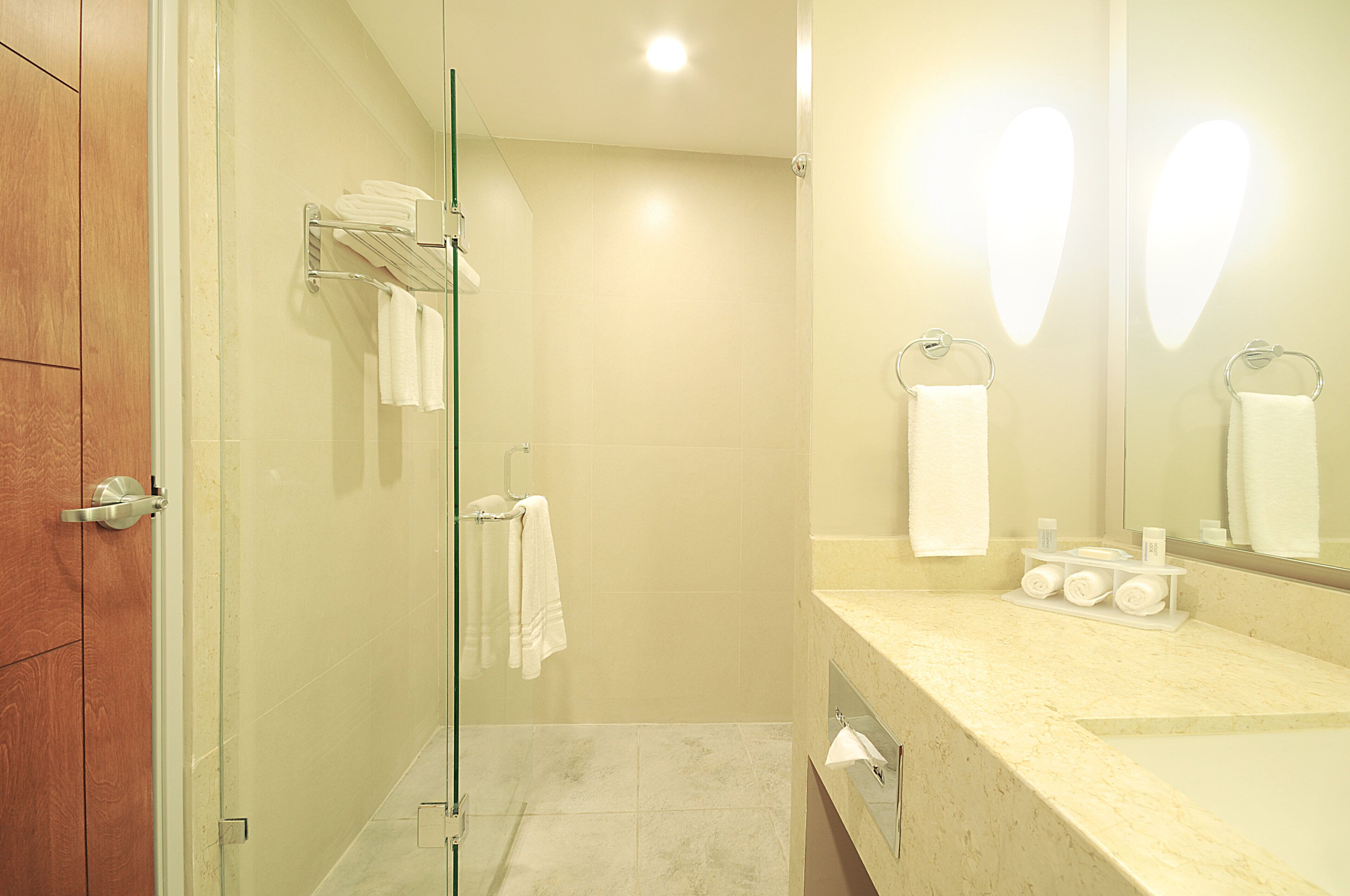 Une salle de bain moderne dotée d’une douche à parois de verre, d’un meuble-lavabo et d’un miroir agrémenté de lumières en forme de cœur.