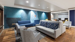 Un salon moderne avec une grande carte murale, un canapé gris, un canapé bleu et une table basse.