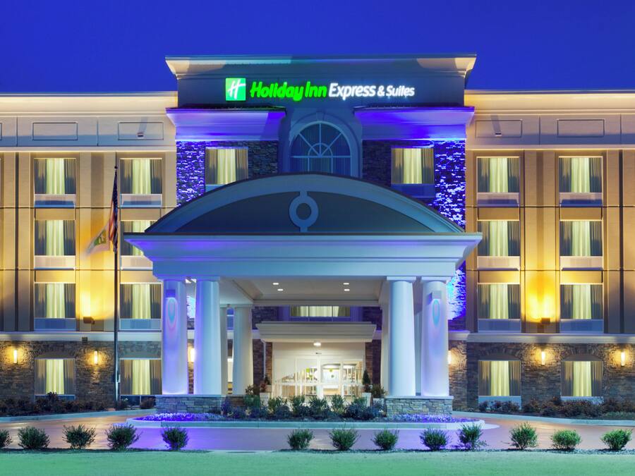 Un hotel Holiday Inn Express & Suites con fachada simétrica, amplias ventanas y una entrada central con arco decorativo.