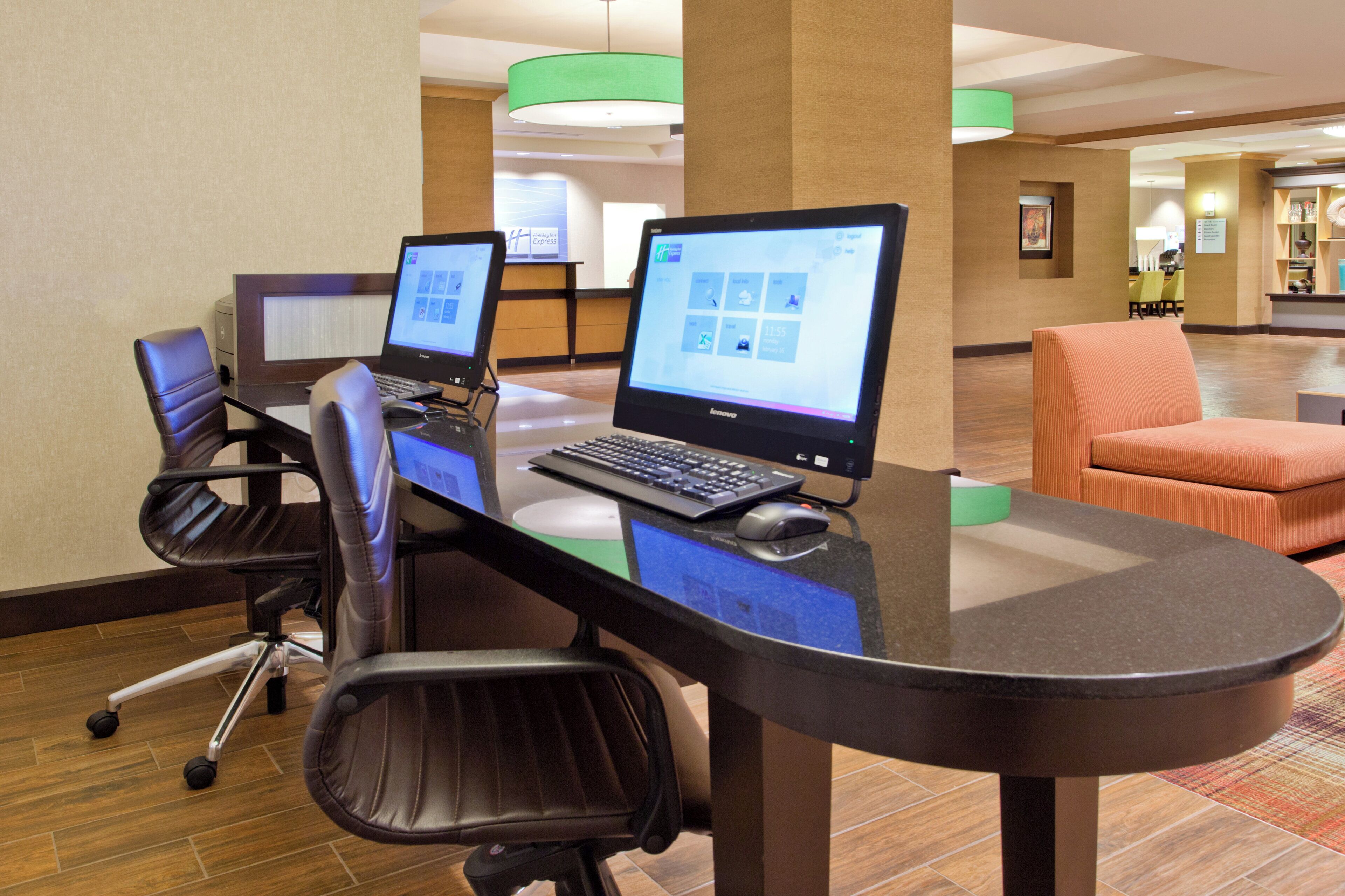 Ein Arbeitsplatz in einem Hotel mit zwei Desktop-Computern, einem Laptop und Bürostühlen.