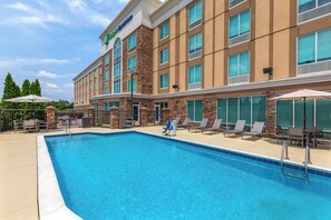 Un hôtel doté d’une piscine, d’un espace extérieur aménagé et d’une façade en pierre.