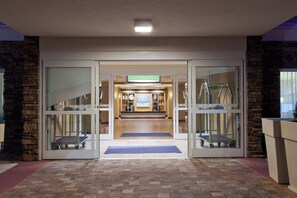 L’entrée d’un hôtel, avec une porte en verre, une rampe et un comptoir d’accueil.