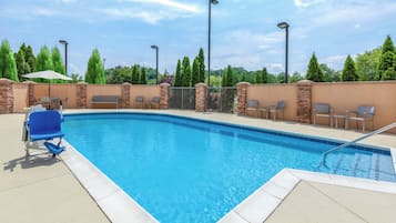 Een seizoensgebonden buitenzwembad en ligstoelen