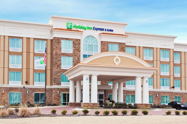 A Holiday Inn Express & Suites hotel with a central entrance, multiple windows, and a flag.