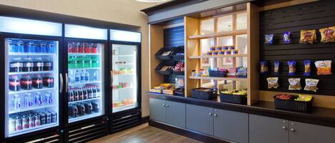 Un área de máquinas expendedoras con diferentes aperitivos y bebidas, incluyendo un refrigerador lleno de refrescos.