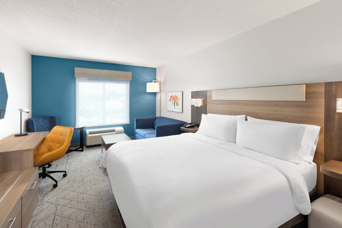 Une chambre d’hôtel avec un grand lit, un bureau, une chaise et une fenêtre.