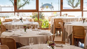 A restaurant with round tables set for dining, large windows with a view of the sea, and outdoor seating. - UNAWAY Imperial Beach Fano (Fano)