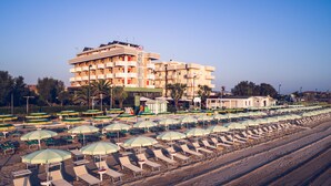A beachfront hotel with multiple floors, rows of beach chairs and umbrellas, and a clear view of the ocean. - UNAWAY Imperial Beach Fano (Fano)