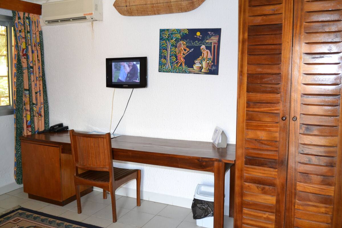 A room with a wooden desk, a chair, a television mounted on the wall, and a door.
