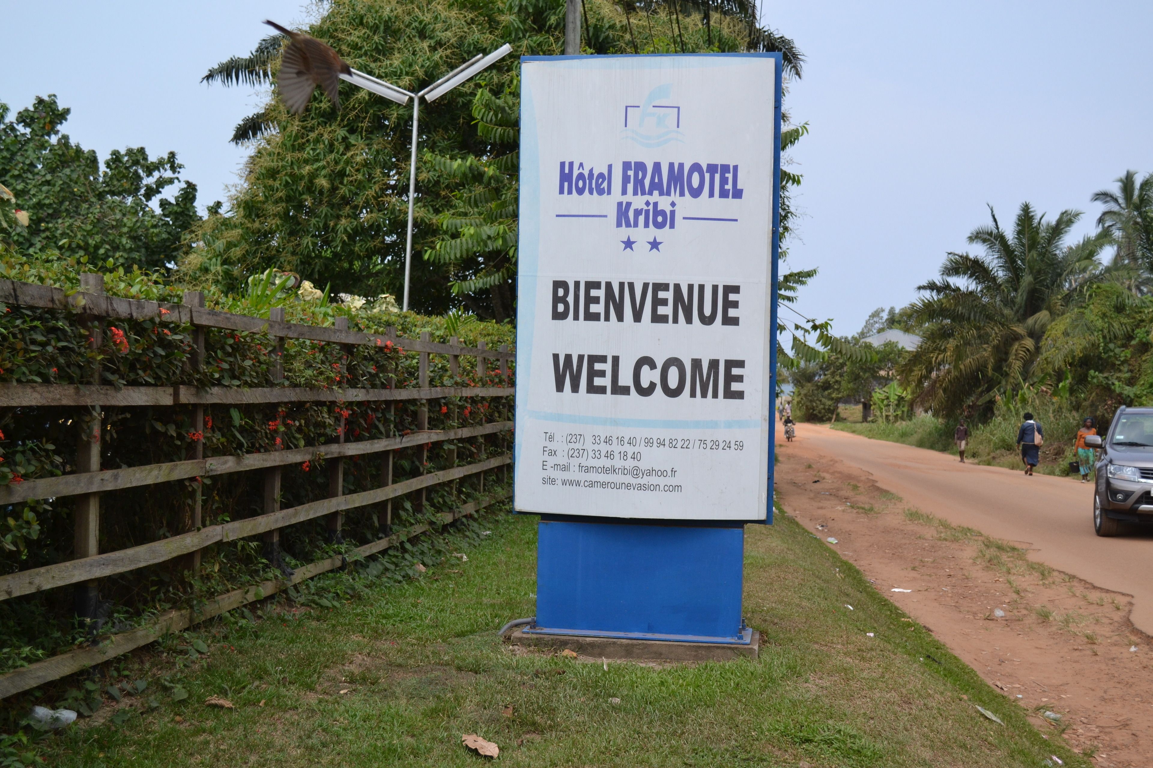 Placa do Hotel Framotel Kribi com informações de contato e uma mensagem de boas-vindas.