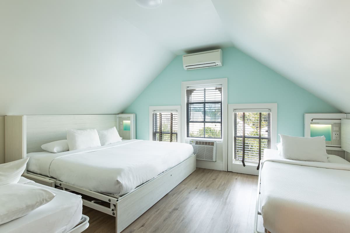 A bedroom with two beds, a skylight, and an air conditioning unit.