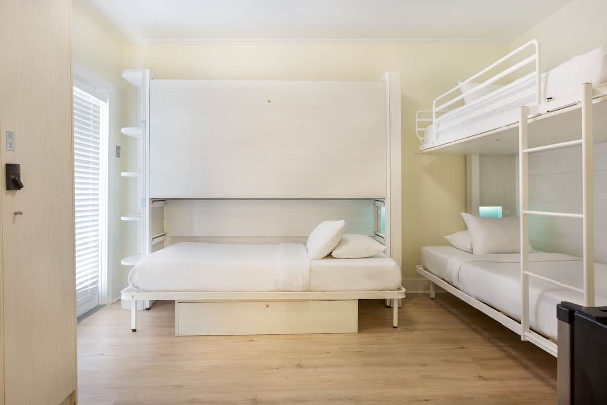 A bunk bed room with a pull-out bed, a desk, and a nightstand.