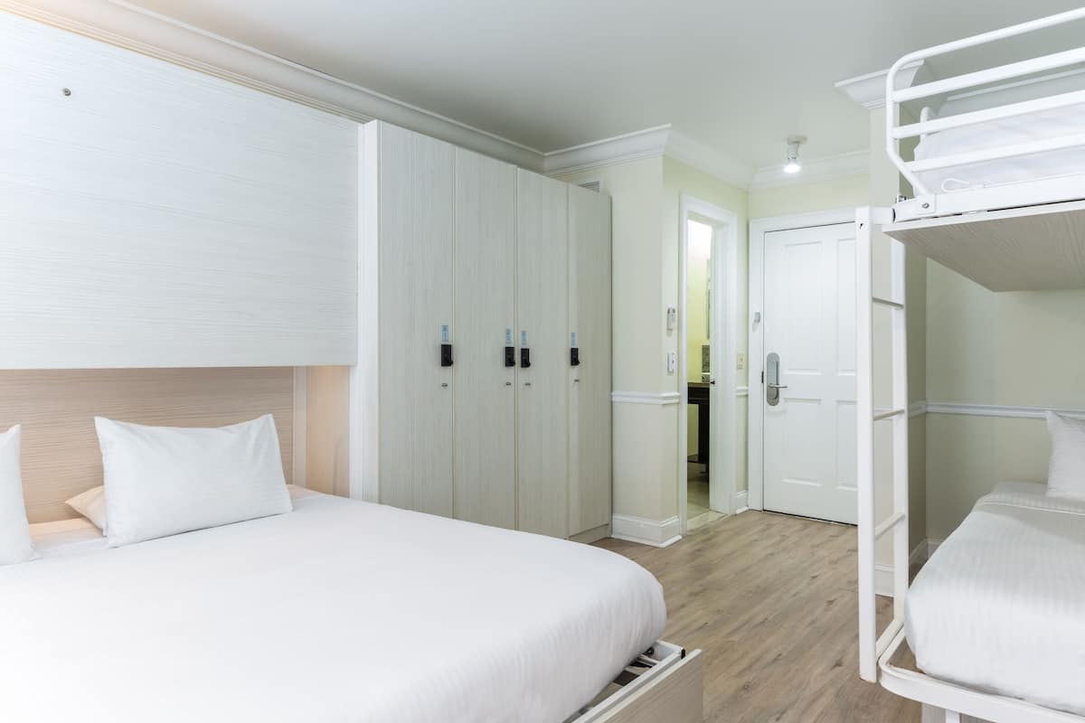 A hotel room with a bunk bed, a large wardrobe, and a separate bathroom.