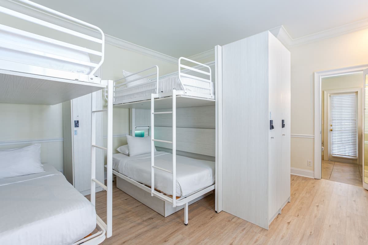 A room with bunk beds, a wardrobe, and a door leading to another room.