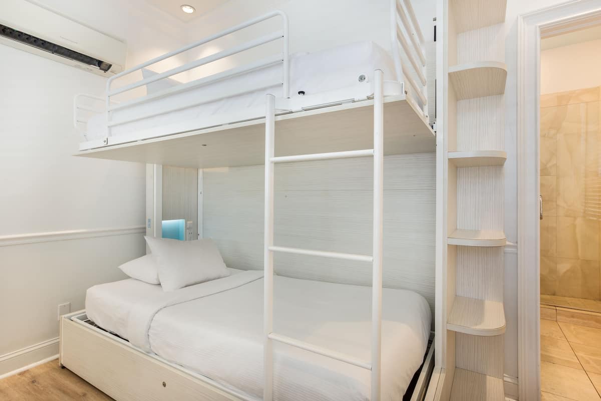 A bunk bed with a ladder, a bedside table, and a built-in shelf unit.