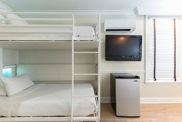 A bunk bed room with a TV and a mini-fridge.