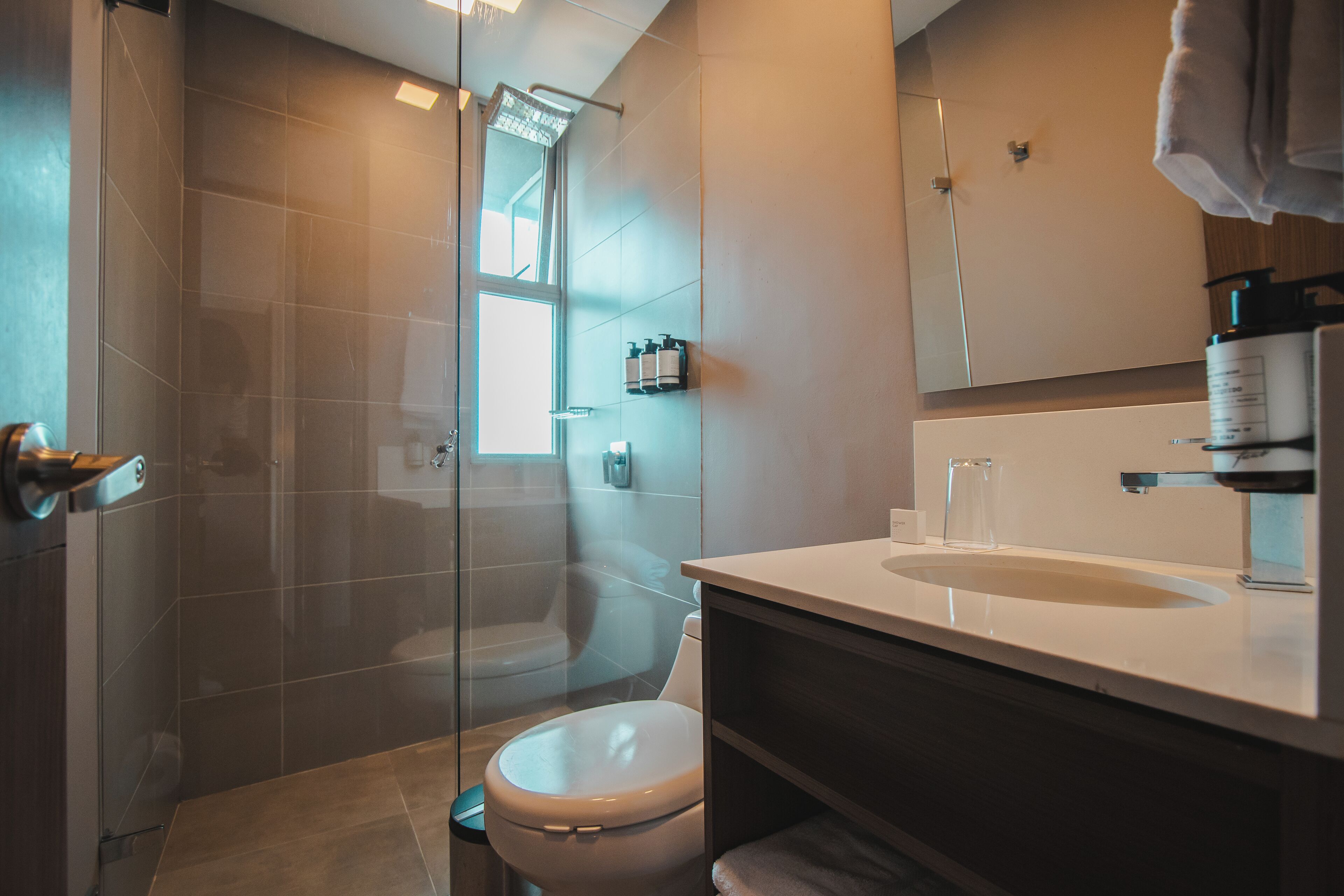 Un baño moderno con ducha de vidrio, inodoro y lavamanos con espejo.
