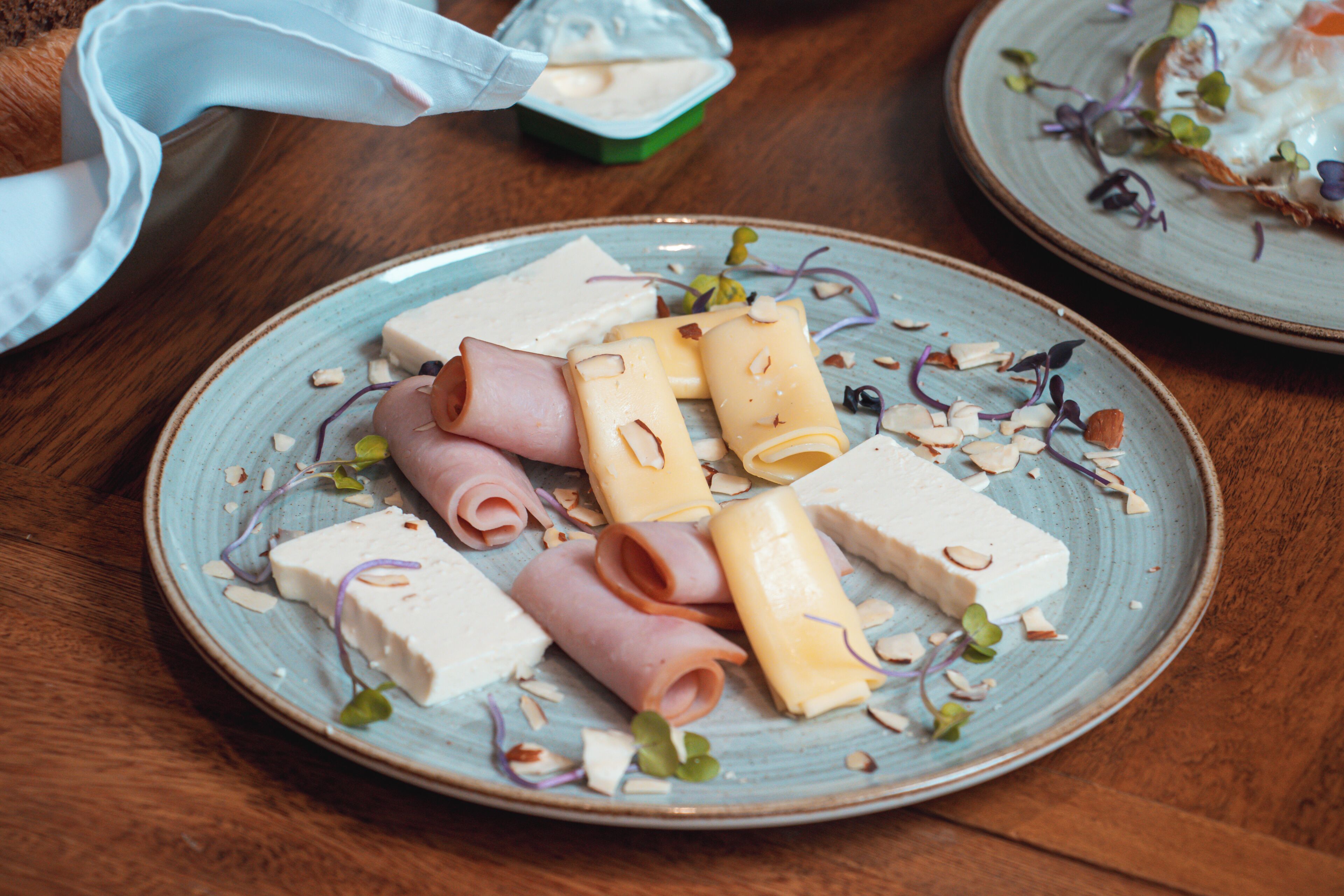 A plate of assorted cheeses and meats on a ceramic plate.